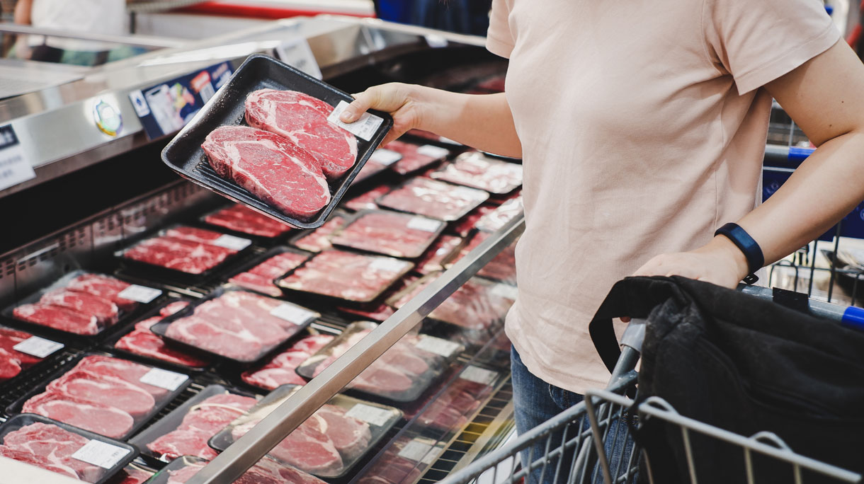 persoon koopt vlees in de supermarkt