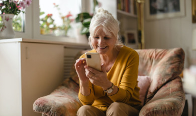 Vrouw met smartphone bezig in de woonkamer, zittend op stoel