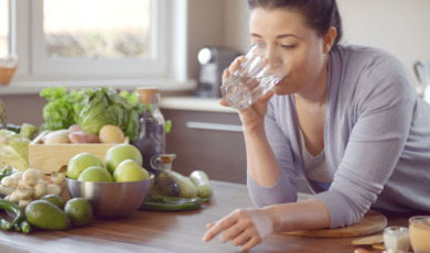 Vrouw doet aan bulkdrinken in de keuken met glas water