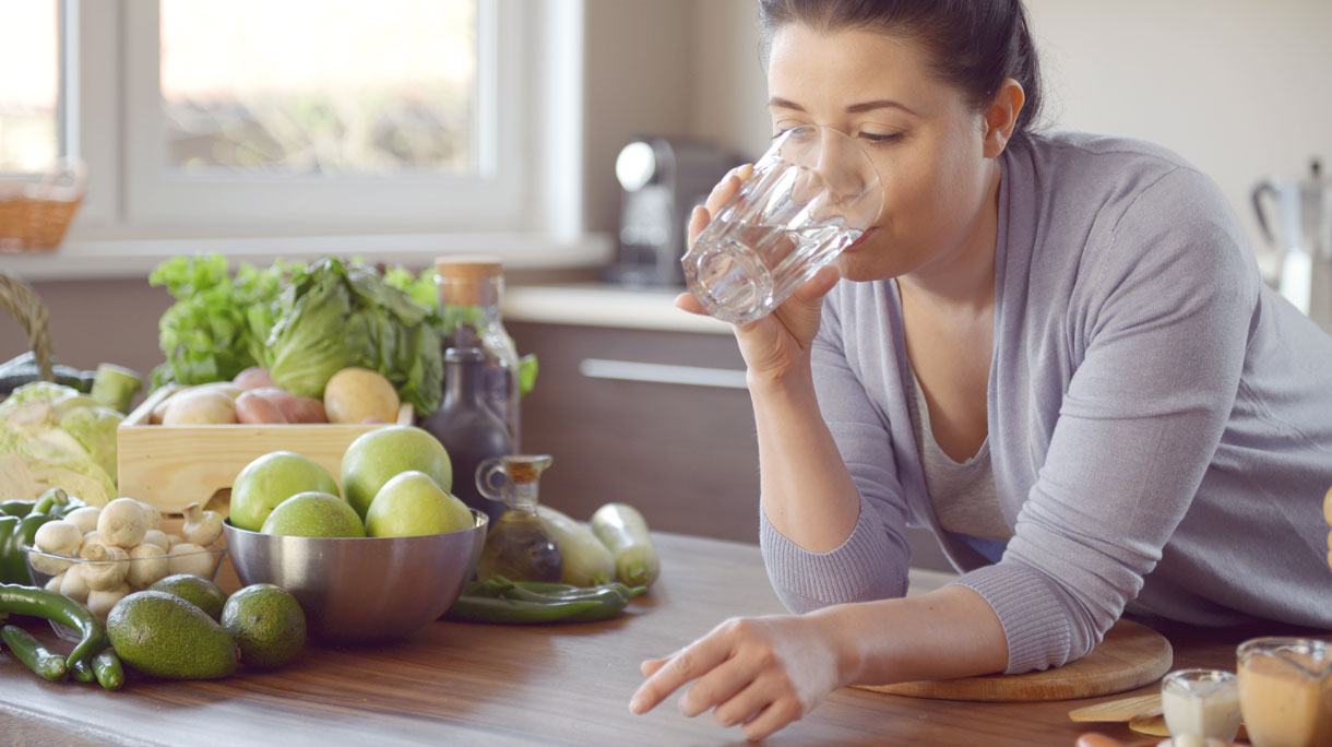 Vrouw doet aan bulkdrinken in de keuken met glas water