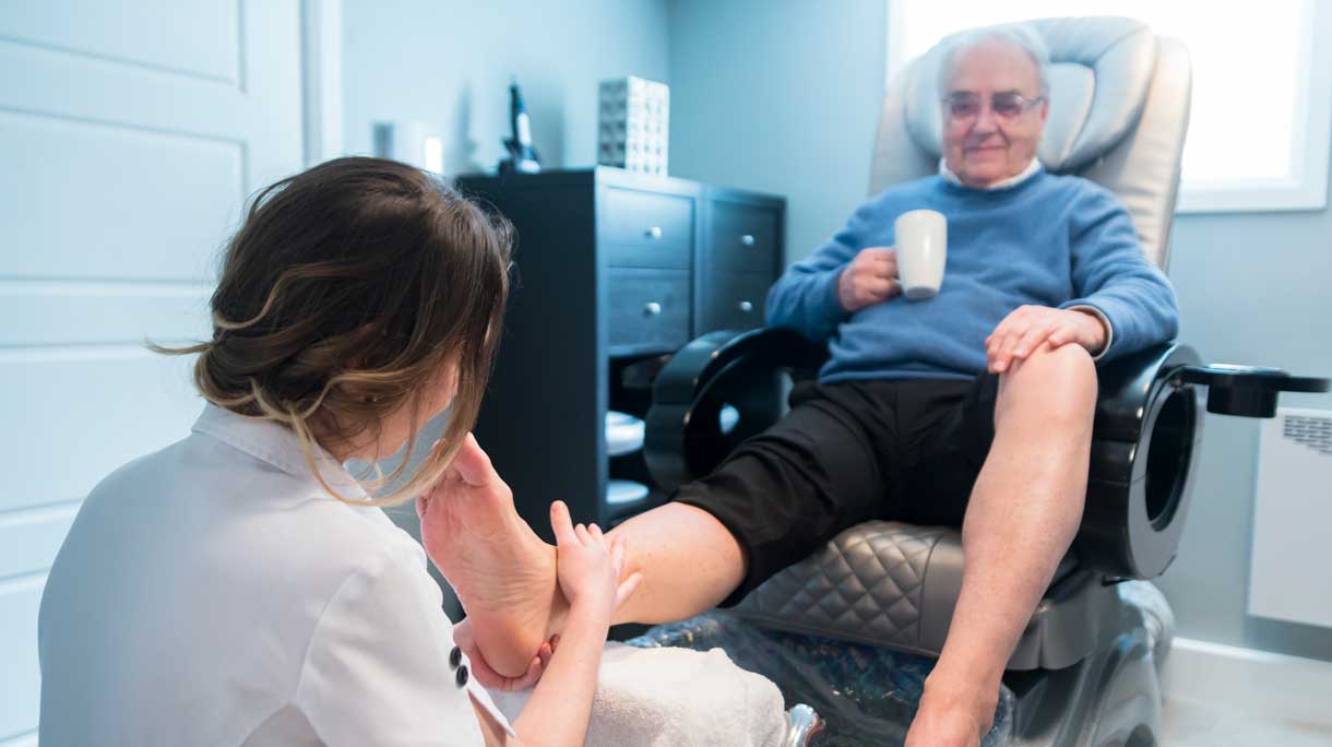 Oudere man zit bij pedicure