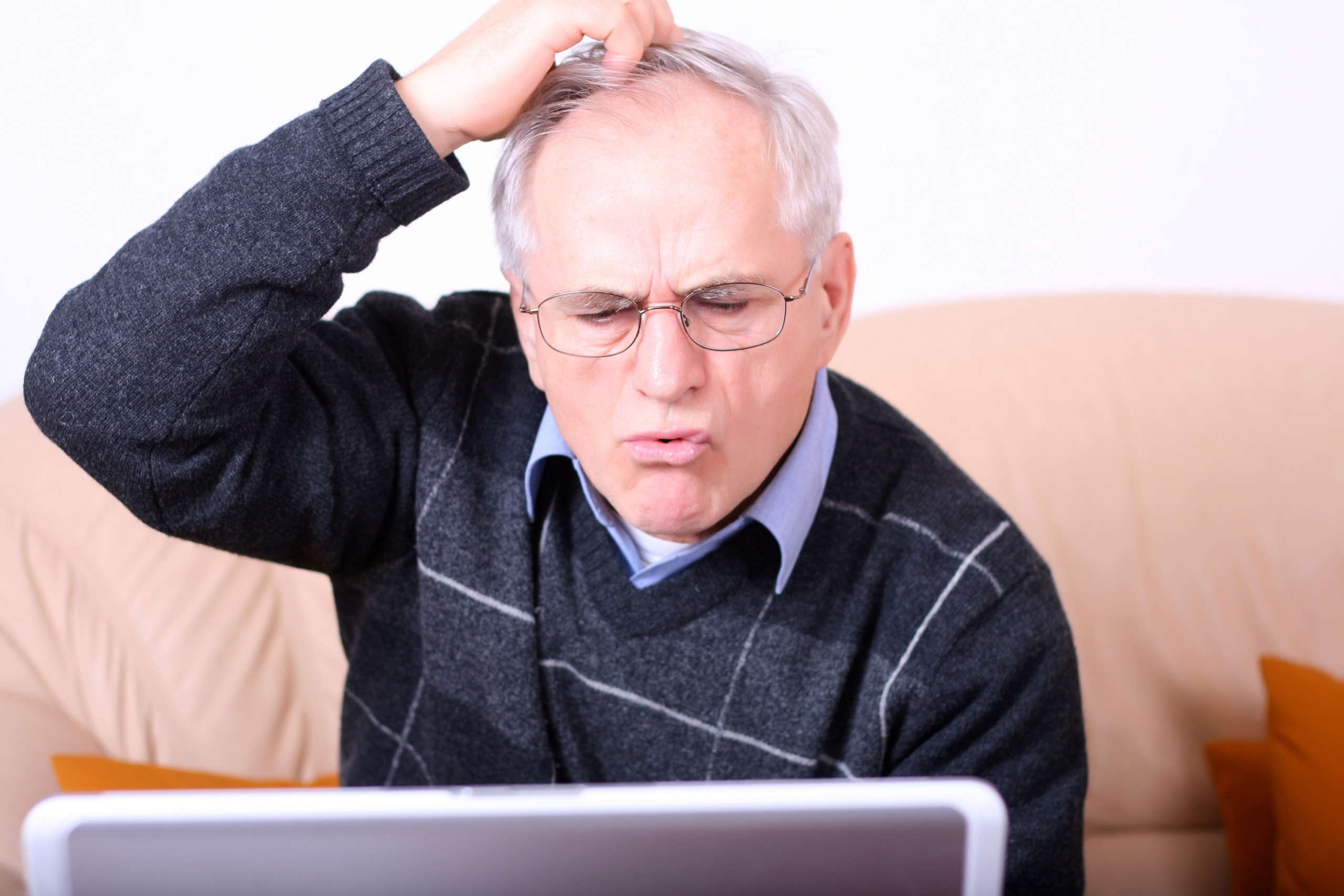 Oudere man krabt op zijn hoofd bij computerproblemen