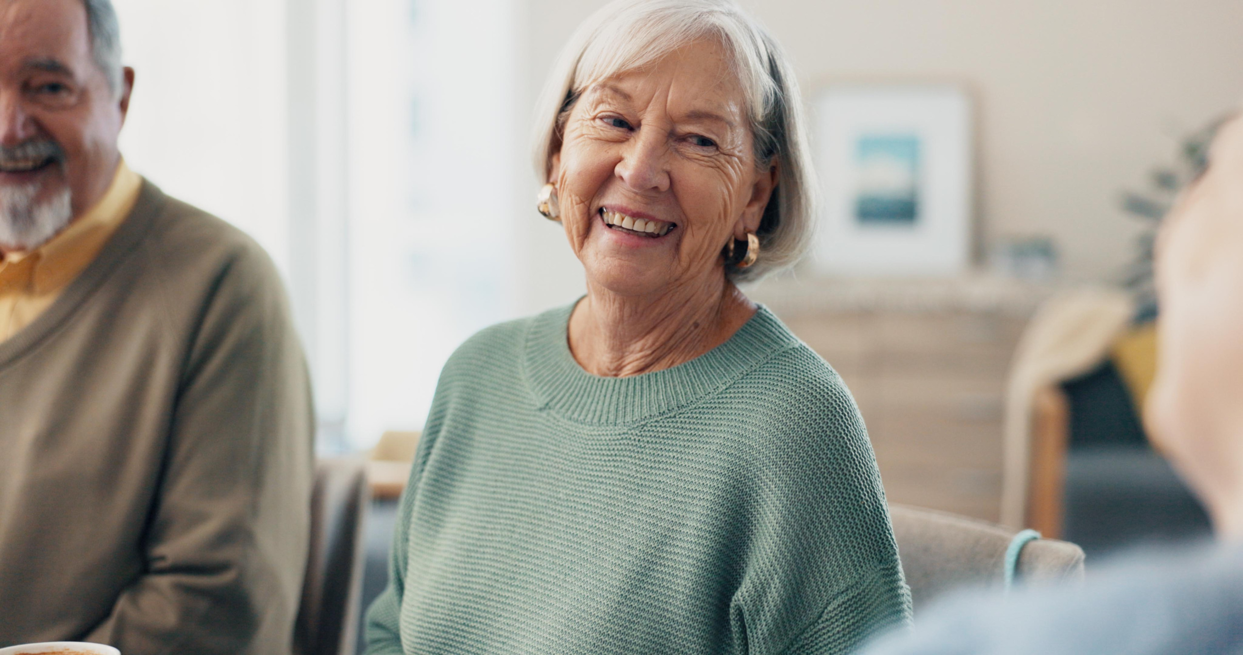 Oudere dame zit aan tafel met leeftijdsgenoten