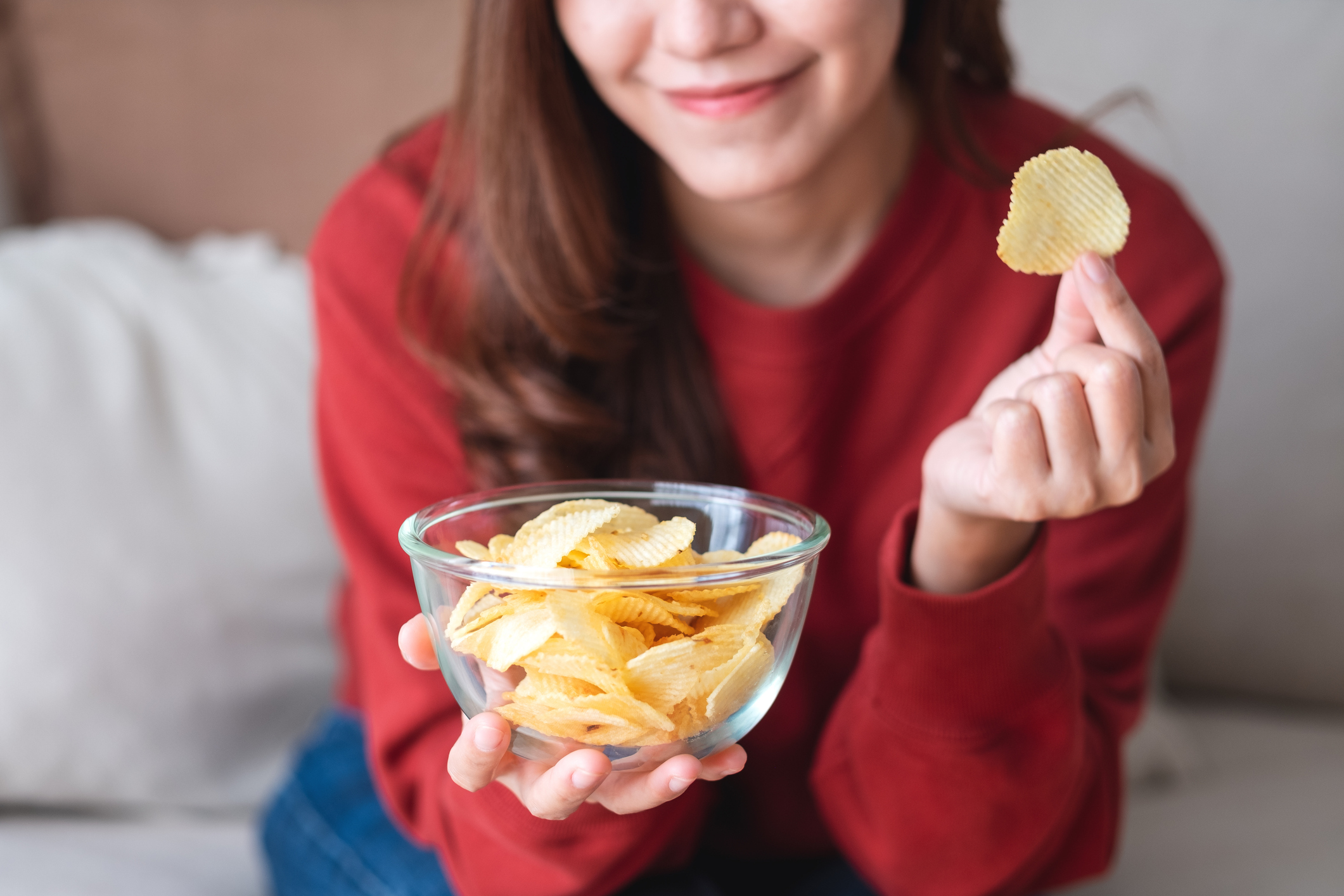 Vrouw eet chips uit kommetje