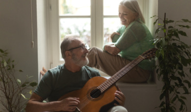 Man speelt gitaar voor zijn vrouw die in de vensterbank zit