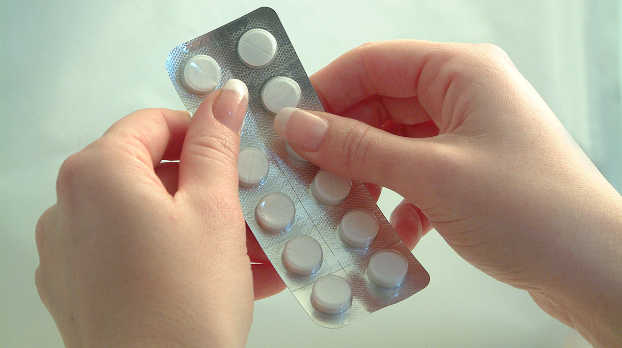 Vrouw drukt tabletten uit pillenstrip paracetamol