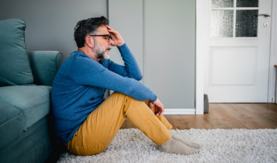 Man zit vertwijfeld op de grond in huis
