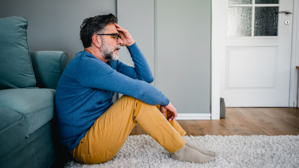 Man zit vertwijfeld op de grond in huis