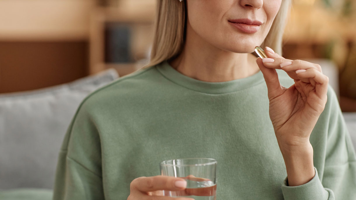 Vrouw neemt vitaminepil in met een glas water