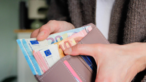 Vrouwelijke hand haalt geld uit portemonnee