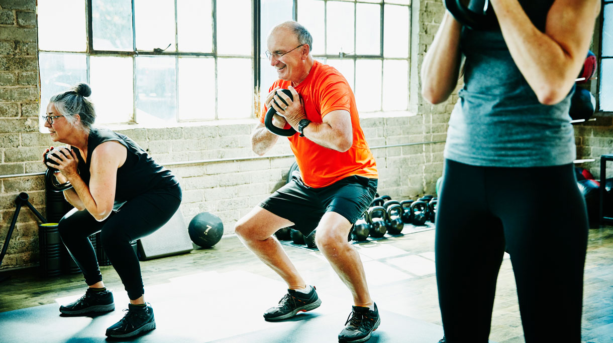 Man en vrouw doen squats met kettlebel en trainen om sterker te worden
