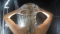 Back of woman’s head in shower washing hair