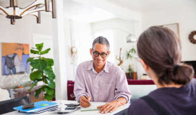 Man is thuis bezig met financien, vrouw zit tegenover hem