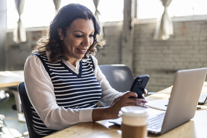 Vrouw in kantoor is bezig met haar smartphone
