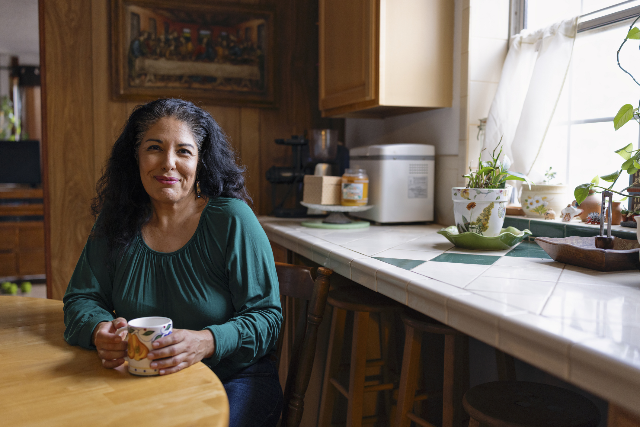 Vrouw met donker haar zit aan de keukentafel