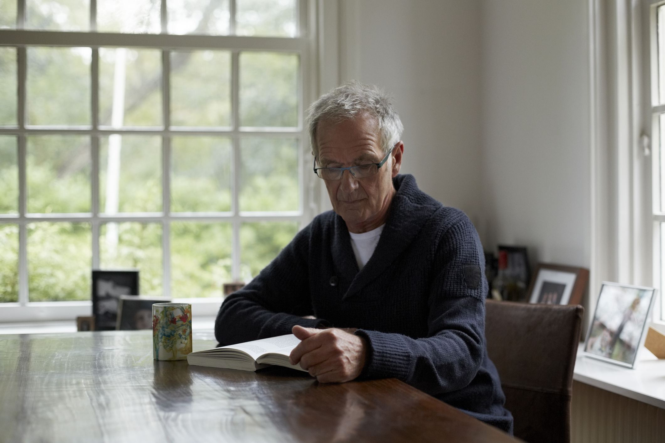 Senior man reading book in cottage