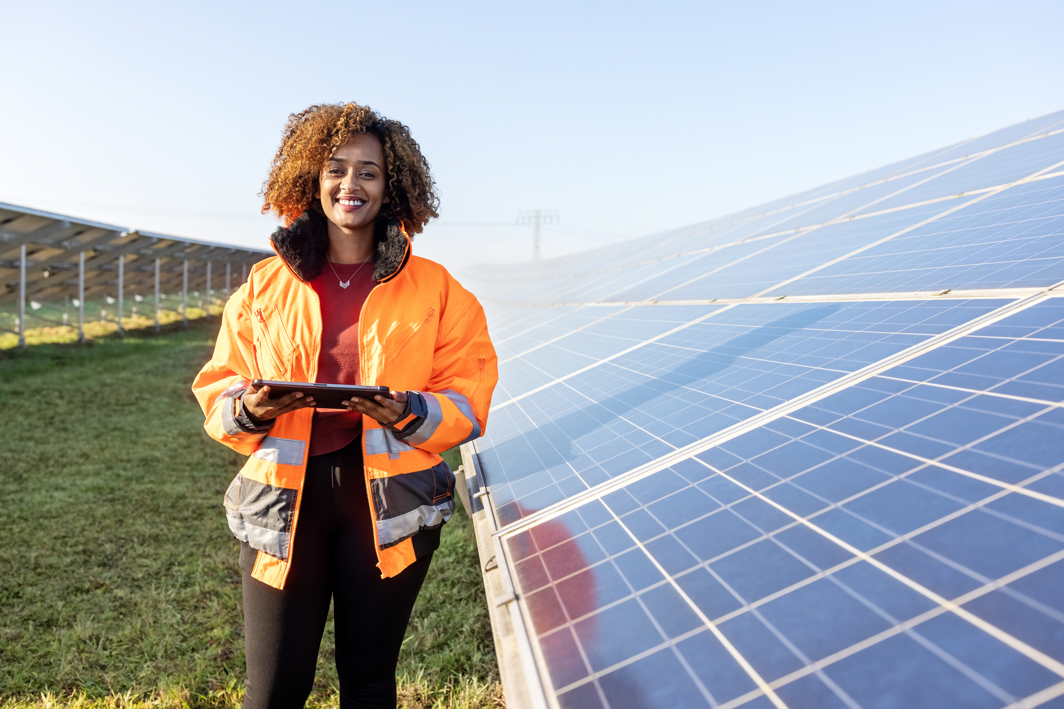 Vrouw staat naast zonnepanelen in een weiland