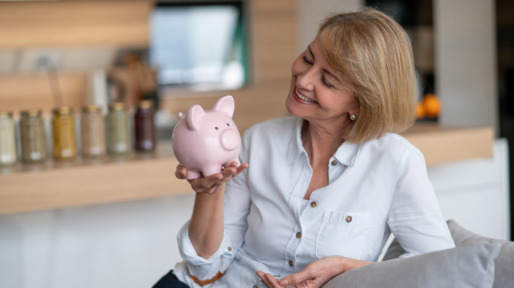 Vrouw heeft mooi spaarvarken in de hand en kijkt lachend