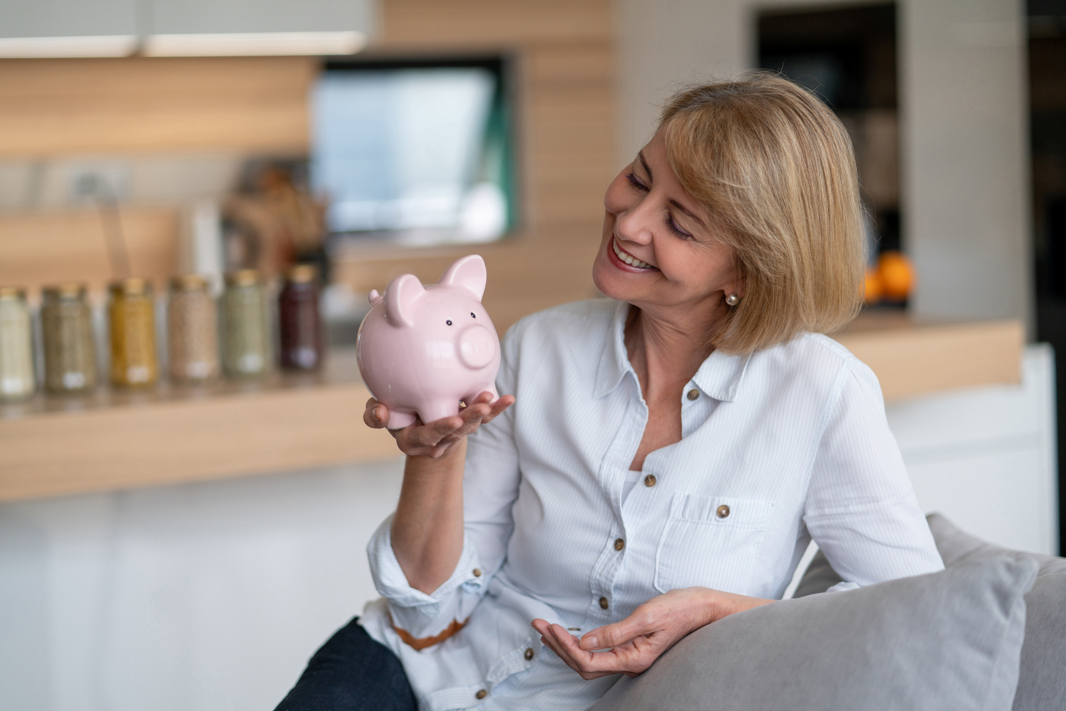 Vrouw heeft mooi spaarvarken in de hand en kijkt lachend