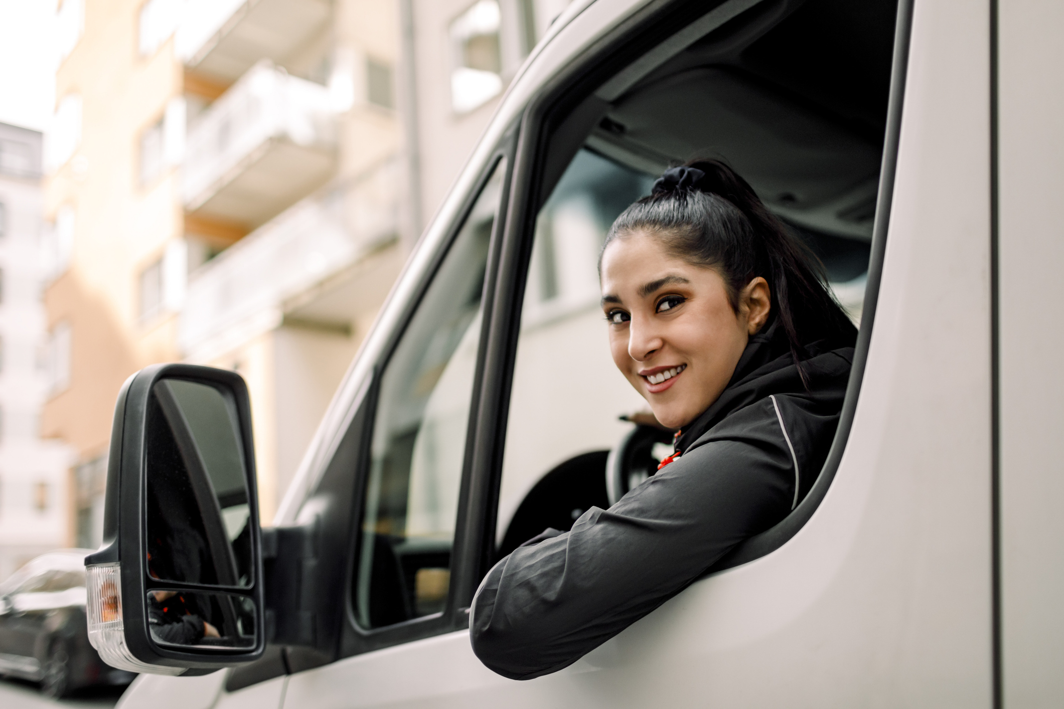 Jonge vrouw in bestelbus kijkt vastbesloten in de camera
