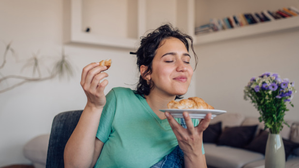 Jonge vrouw eet heerlijke croissant, ogen gesloten