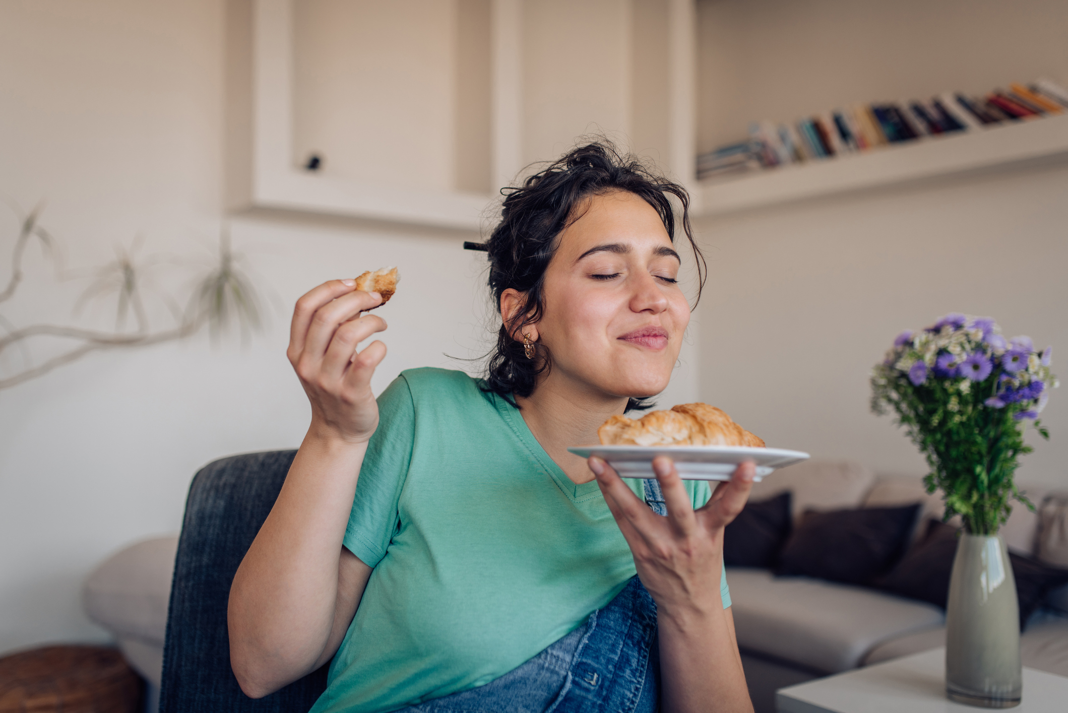 Jonge vrouw eet heerlijke croissant, ogen gesloten