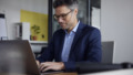 Oudere man met bril en colbert is hard aan het werk op zijn laptop