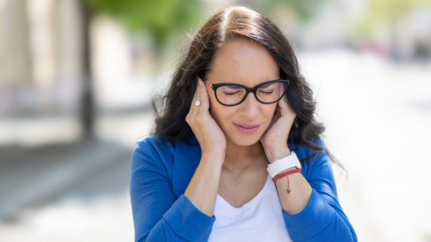 Vrouw heeft last van herrie en drukt haar oren dicht