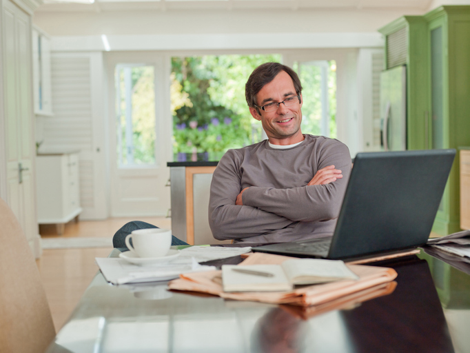 Man is thuis bezig achter zijn laptop
