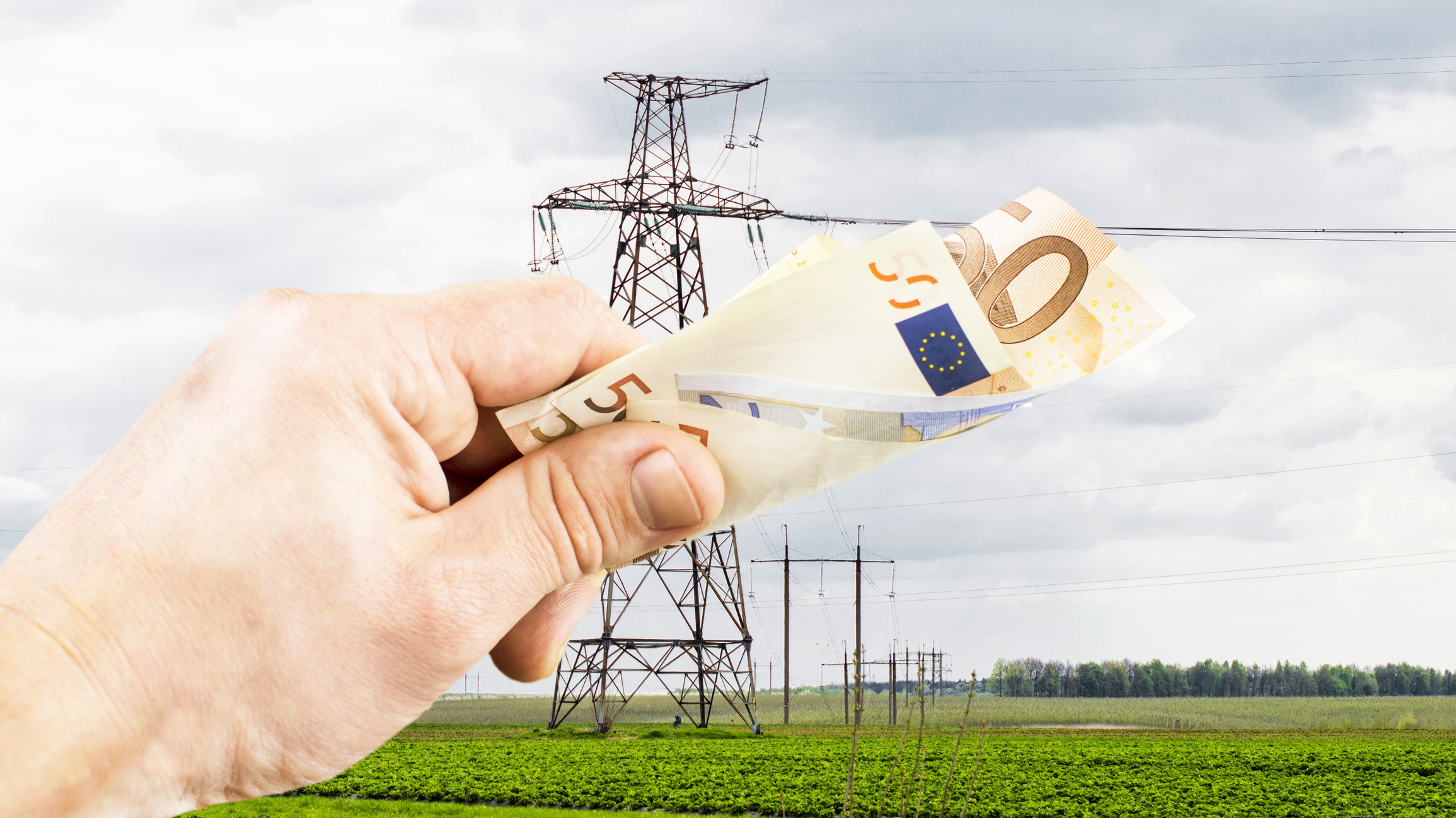 Eurobiljes wordt vastgehouden door mensenhand, energiemast op de achtergrond