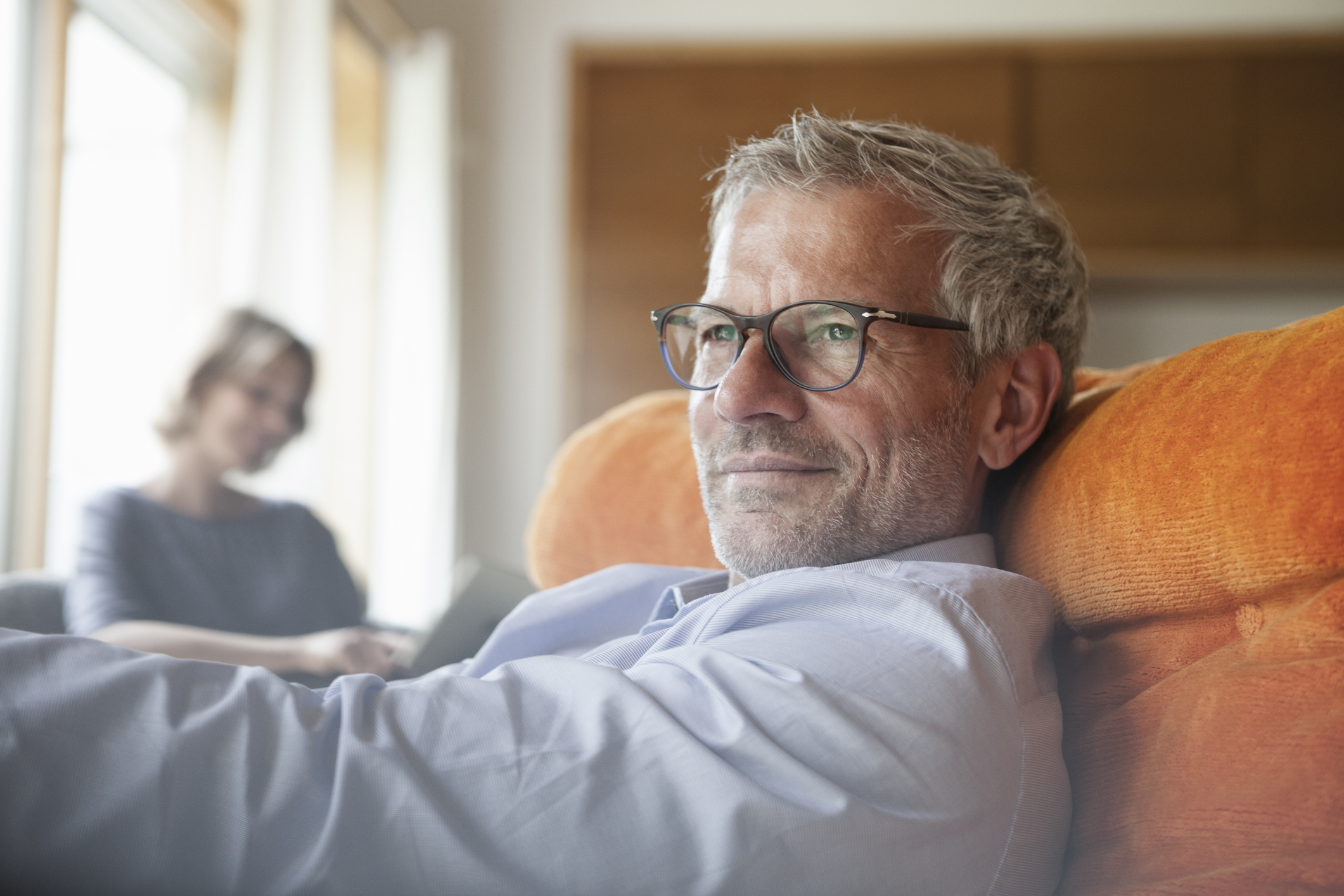 Oudere man zit ontspannen in fauteuil