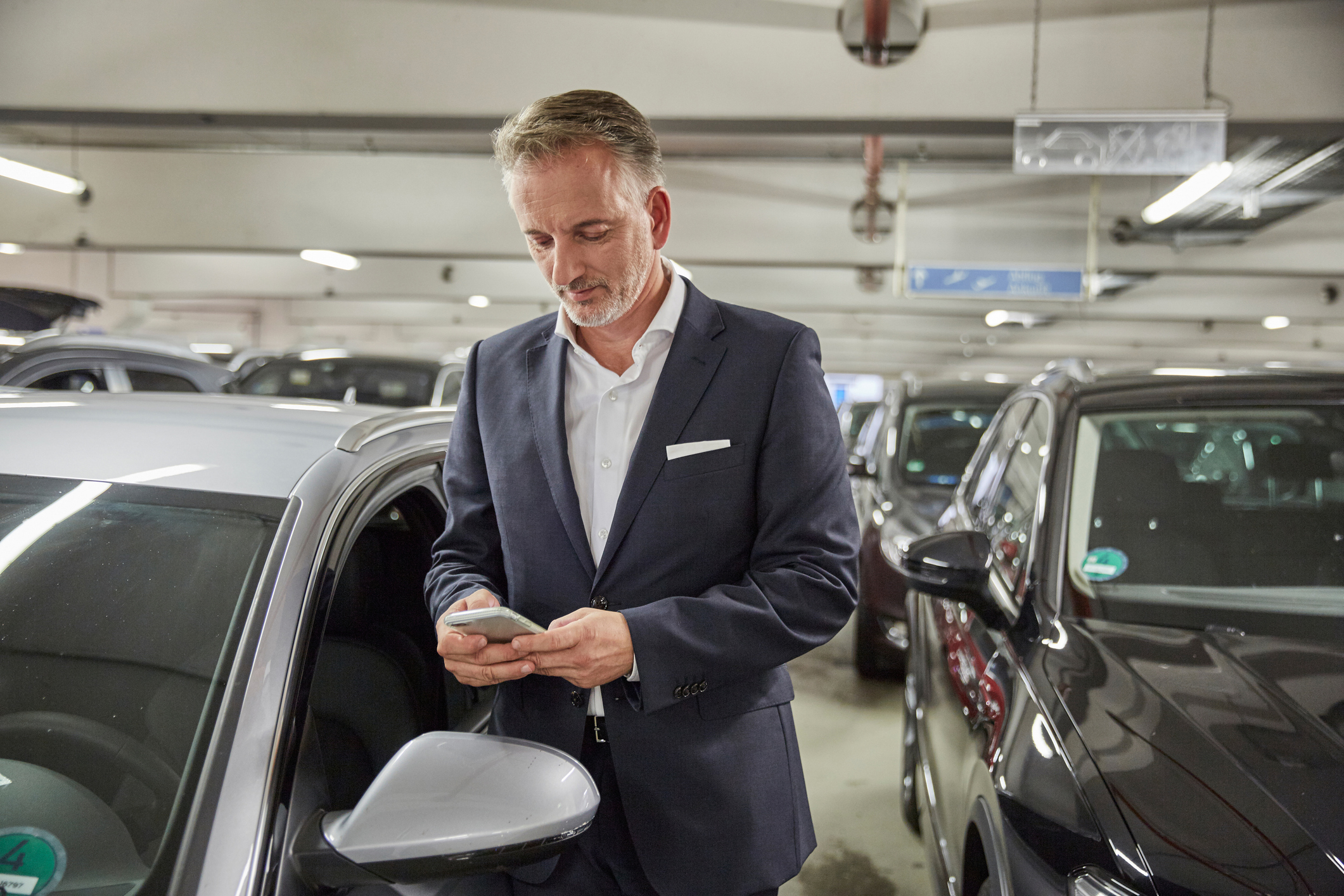 Man checkt smartphone nadat zijn auto is geparkeerd