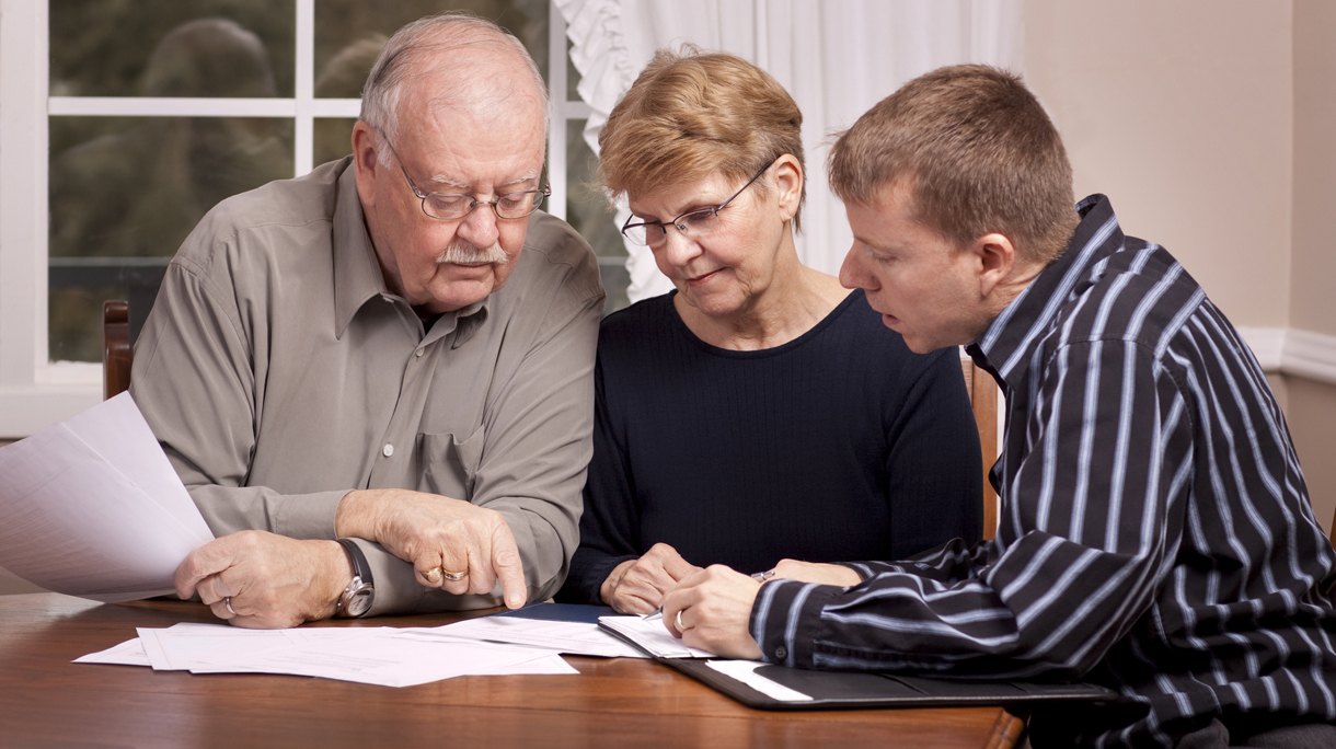 Financial advisor with senior couple going over paperwork