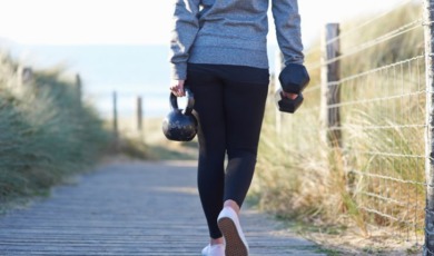 vrouw traint met gewicht op strand.