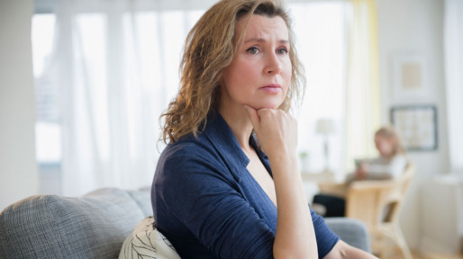 Vrouw zit op de bank kijkt zorgelijk