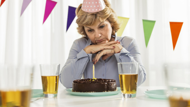 Vrouw viert verjaardag alleen met chocoladetaart, sip gezicht