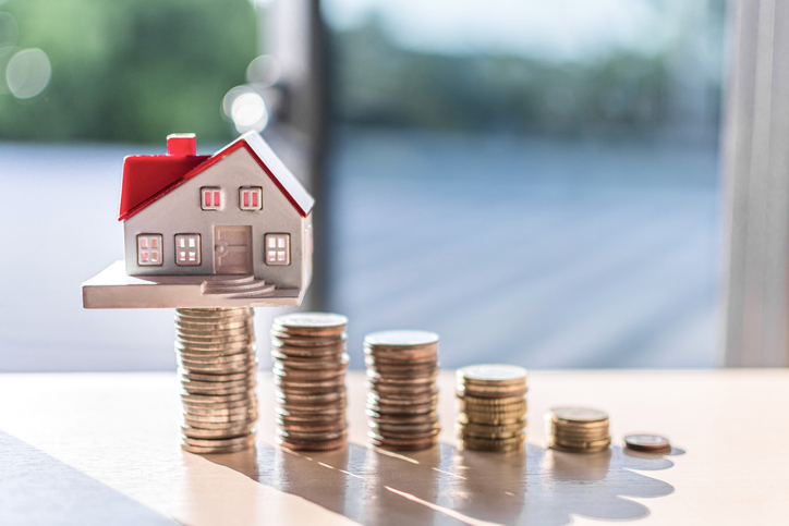 Woningprijs, huisje op een stel gestapelde munten