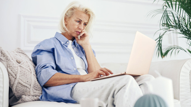 Vrouw op de bank zit op een computer te kijken