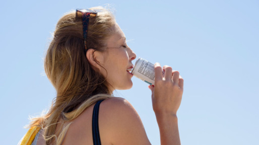 Vrouw drinkt in de warme zon een blikje fris