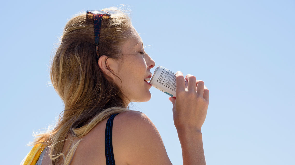 Vrouw drinkt in de warme zon een blikje fris