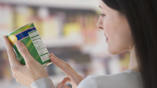 Vrouw leest etiket op een blik in de supermarkt
