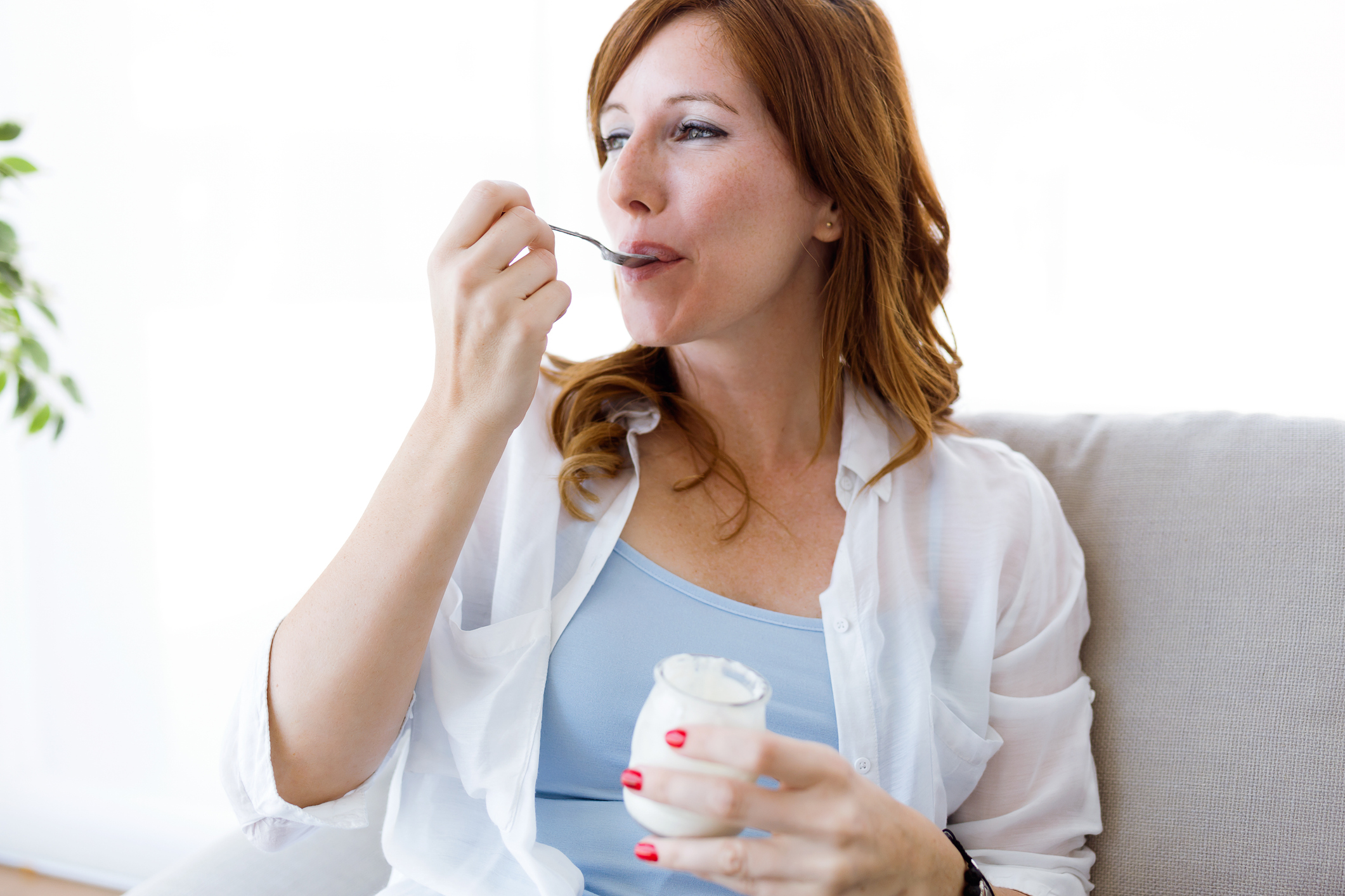 Vrouw eet crème fraîche op de bank