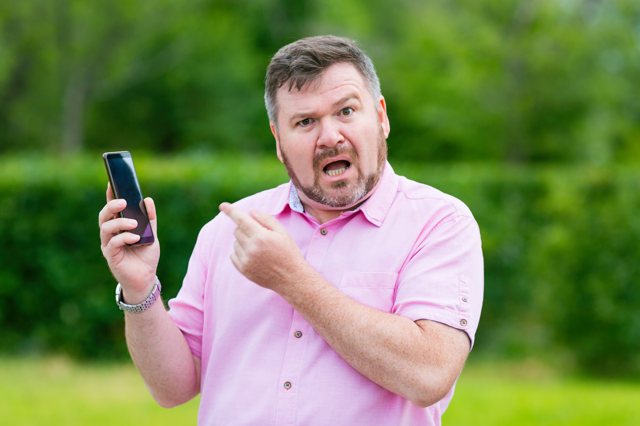 Man is boos en verongelijkt aan de telefoon in de tuin