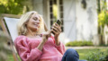 Vrouw zit in tuinstoel met haar smartphone te spelen