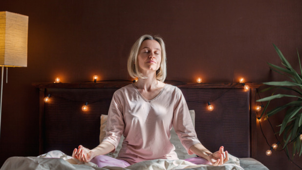 Vrouw doet yoga-oefening op bed voor het slapengaan