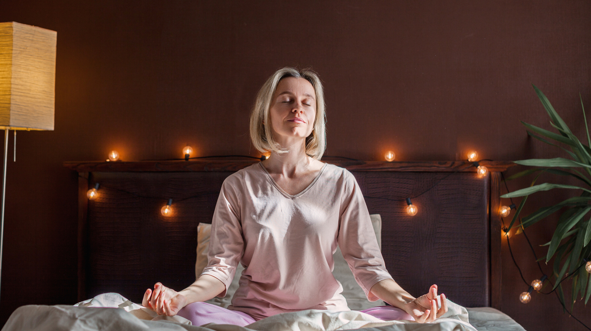 Vrouw doet yoga-oefening op bed voor het slapengaan