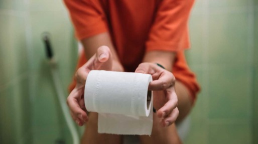 Vrouw op toilet met toiletrol