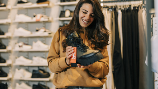 Jonge vrouw koopt schoenen in winkel