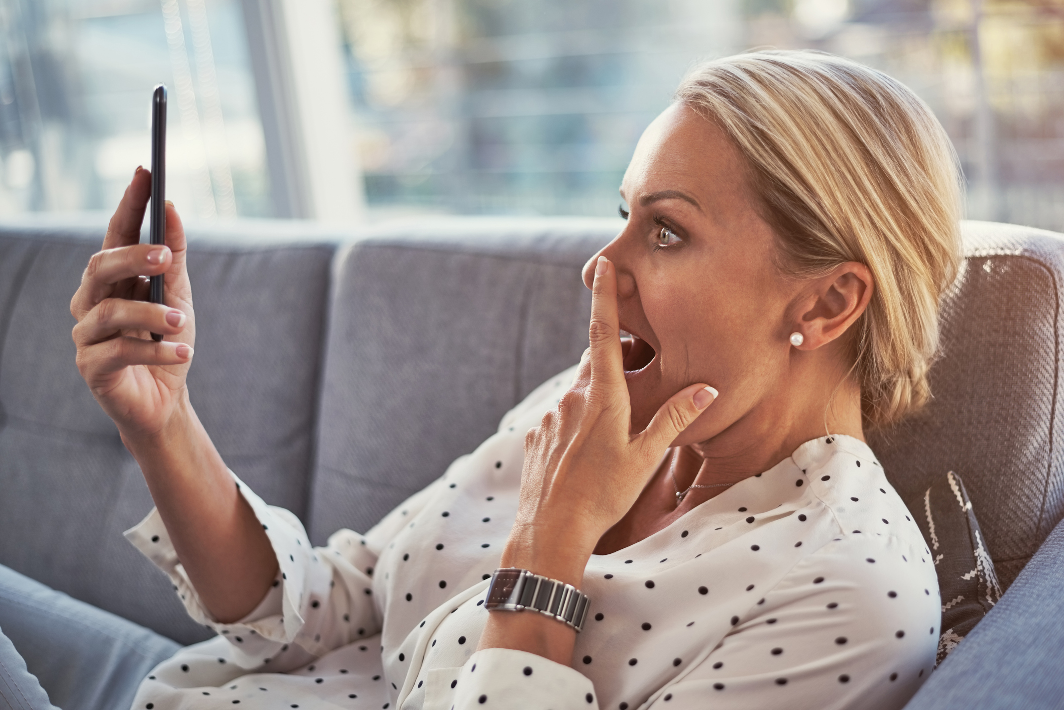 Vrouw is verbaasd bezig met haar mobiele telefoon