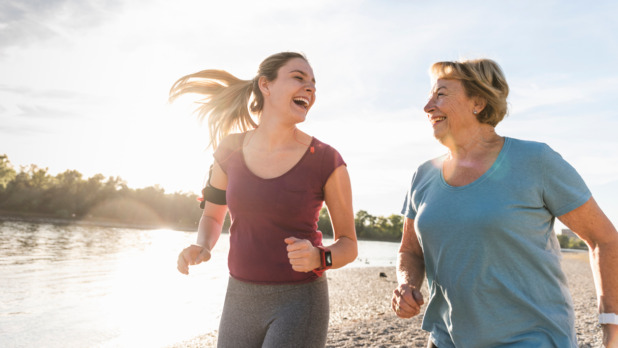 Moeder en dochter rennen in de zon met activity tracker om de pols